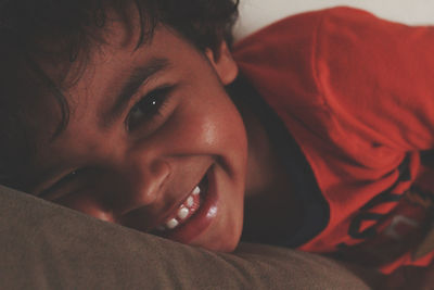 Close-up portrait of boy relaxing on bed at home