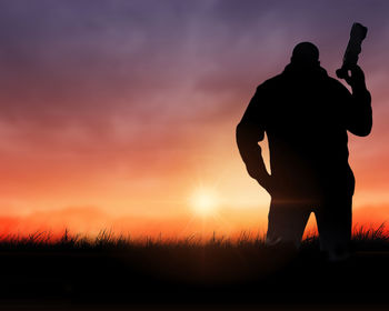 Silhouette man standing on field against sky during sunset