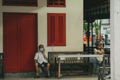 Full length of man sitting on chair against window