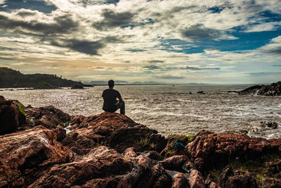 Rear view of man looking at sea against sky