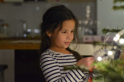 Close-up of girl holding christmas tree at home