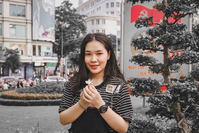 Portrait of smiling young woman standing against building