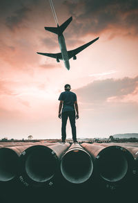 Man looking at airplane flying against sky