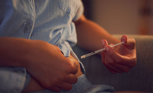 Midsection of man holding syringe