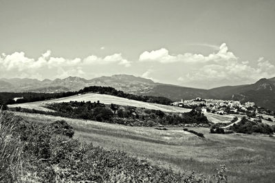 Scenic view of field by mountains against sky