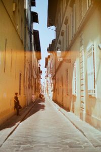 Man walking on alley amidst street in city