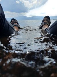 Low section of person in sea against sky