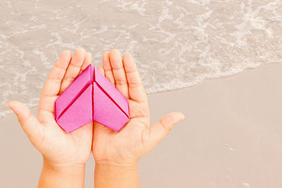 Close-up of hand holding umbrella over sea