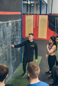 High angle view of instructor explaining over blackboard to athletes in gym