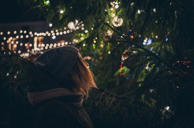 Woman looking at christmas tree at night