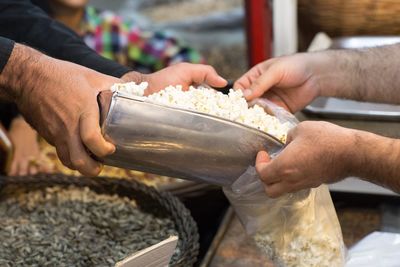 Cropped hand of vendor selling popcorns to customer at market