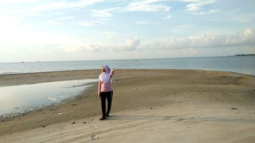 Rear view of woman on beach against sky