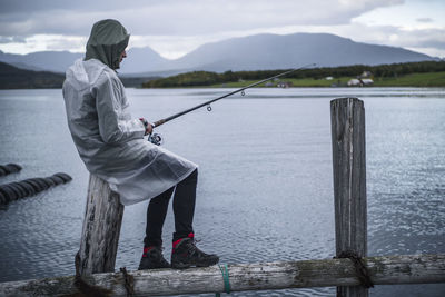 Man fishing in river against mountains