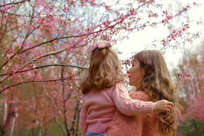 Mother and little daughter, in the park under a flowering cherry tree