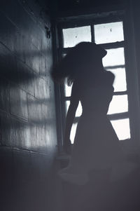 Silhouette woman standing in window