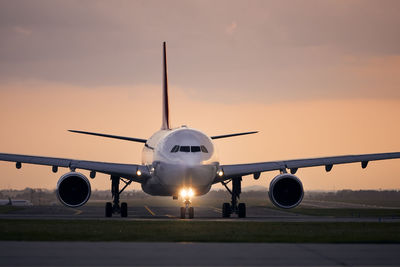 Wide-body airplane taxiing for take off. front view of plane against airport at sunset.