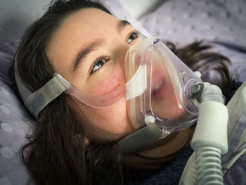 Close-up of girl wearing gas mask while lying down on bed