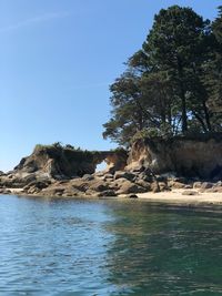 Rock formation by sea against clear sky