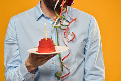 Midsection of man cupcake against colored background