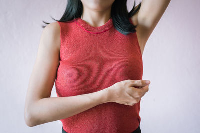 Midsection of woman standing against red wall