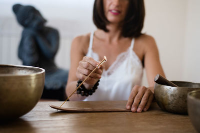 Midsection of woman burning incense on table