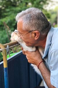 Senior man smiling while holding cat in balcony