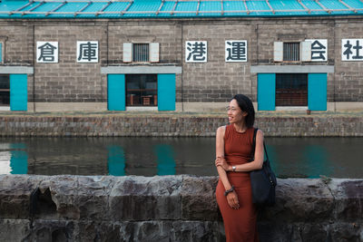 Smiling woman looking away against canal