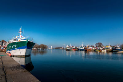 Ship moored at harbor against clear blue sky