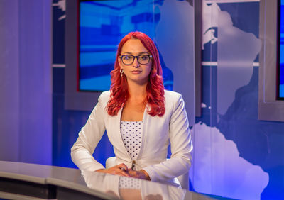 Portrait of confident young newscaster sitting at television studio