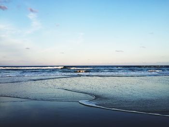 View of calm beach against blue sky