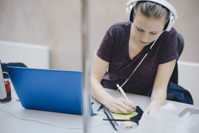 Female computer programmer writing on adhesive note while working in office