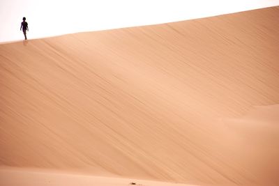 Boy walking on sand dune