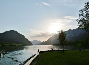 People enjoying at lake against sky