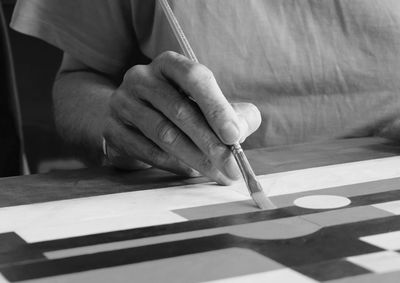 Midsection of man holding paper with text on table