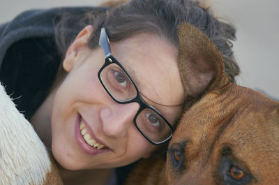 Close-up portrait of smiling young woman wearing eyeglasses with dog at beach