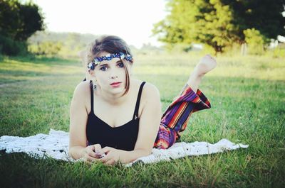 Portrait of young woman lying on grassy field