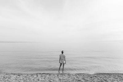 Rear view of man standing on beach against sky