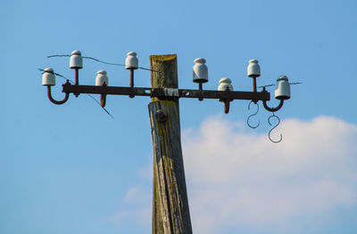 Low angle view of an old electricity mast against sky