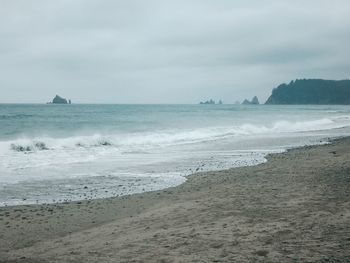 Scenic view of beach against cloudy sky