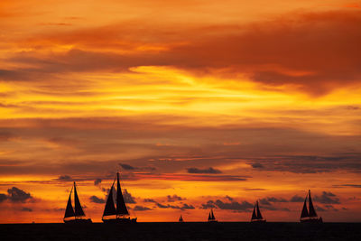 Ships sailing on sea against cloudy sky at sunrise