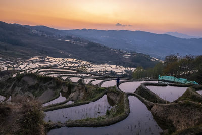 Scenic view of river by mountains against sky during sunset