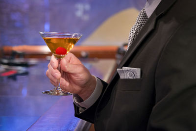 Midsection of man holding drink in martini glass