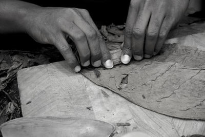 Cropped hands holding making cigar in workshop
