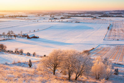 Scenic view of snow covered field against sky during sunset