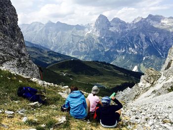 High angle view of hikers relaxing on peak while looking at mountain range