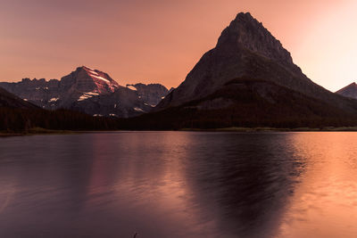 Scenic view of lake by mountains against sky during sunset