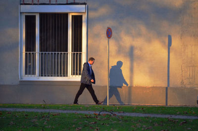 Rear view of men walking on street against building