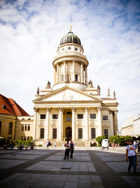 Tourist walking in front of building against sky