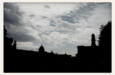 Silhouette of building against cloudy sky at sunset