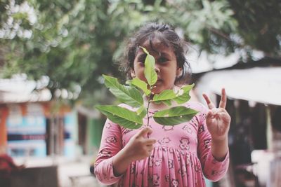 Midsection of woman holding leaves while standing by plant